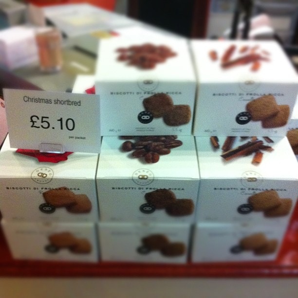Boxed biscuits displayed on a shelf with a price label reading Christmas shortbread £5.10.
