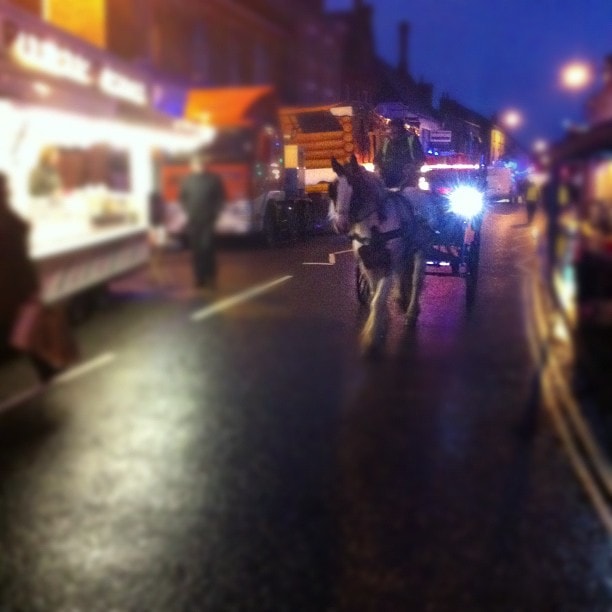 Emergency vehicles with flashing lights parked on a wet street at night, with pedestrians and buildings visible in the background.