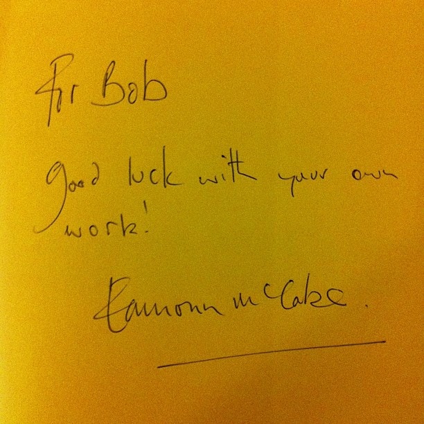 Handwritten note on yellow paper reading For Bob, Good luck with your own work, Eamon McCabe with a signature line.