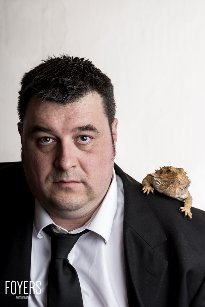 Man with lizard on shoulder in suit.