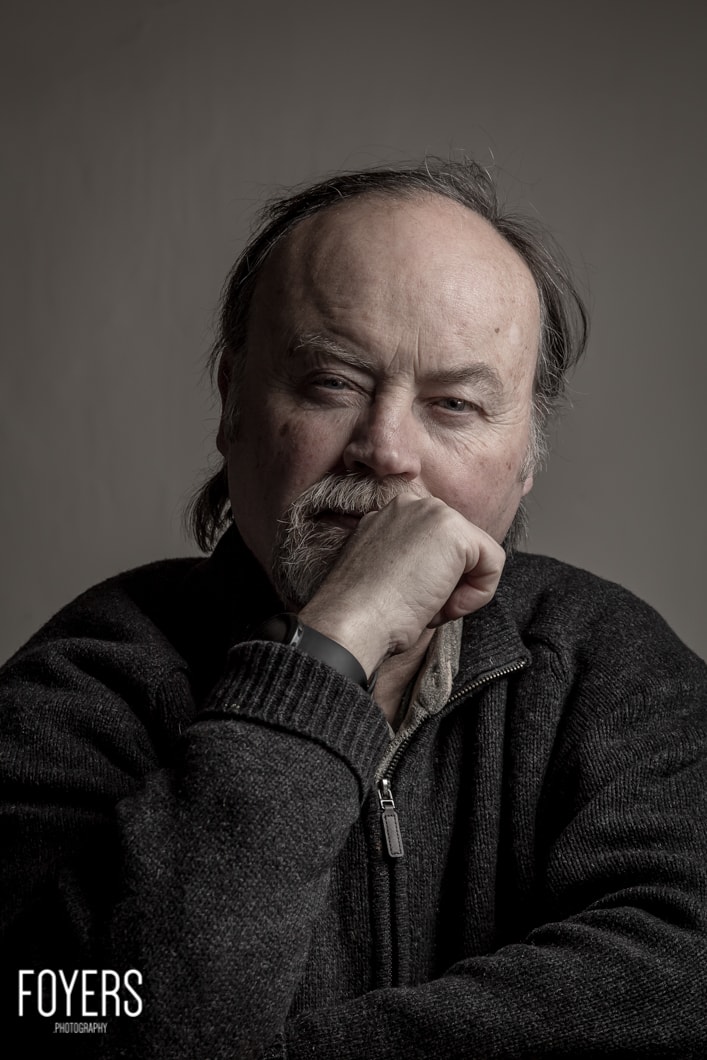 Thoughtful man posing, hand on chin, neutral background.