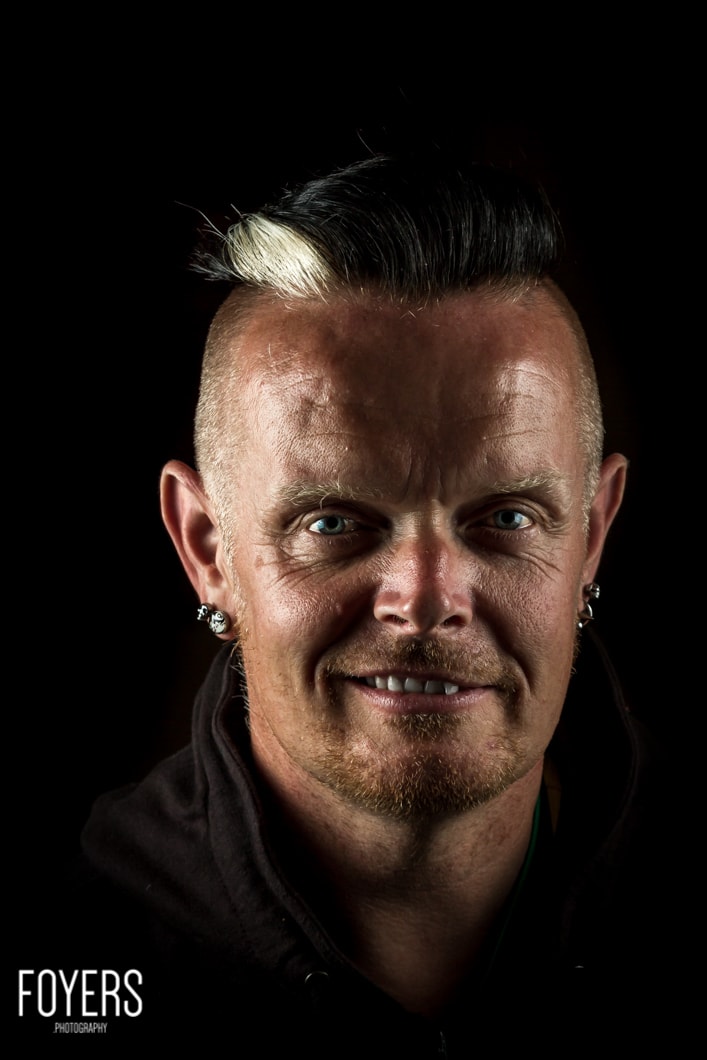 Smiling man with distinctive hairstyle and earrings