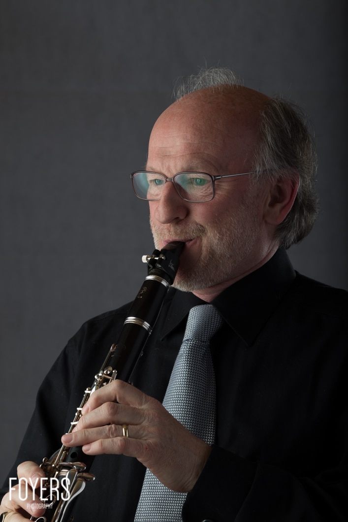 Man playing a clarinet in a suit.