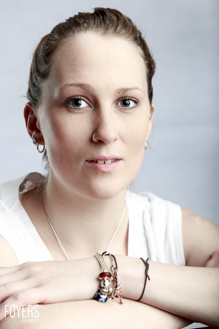 Woman with bracelets and nose piercing, studio portrait.