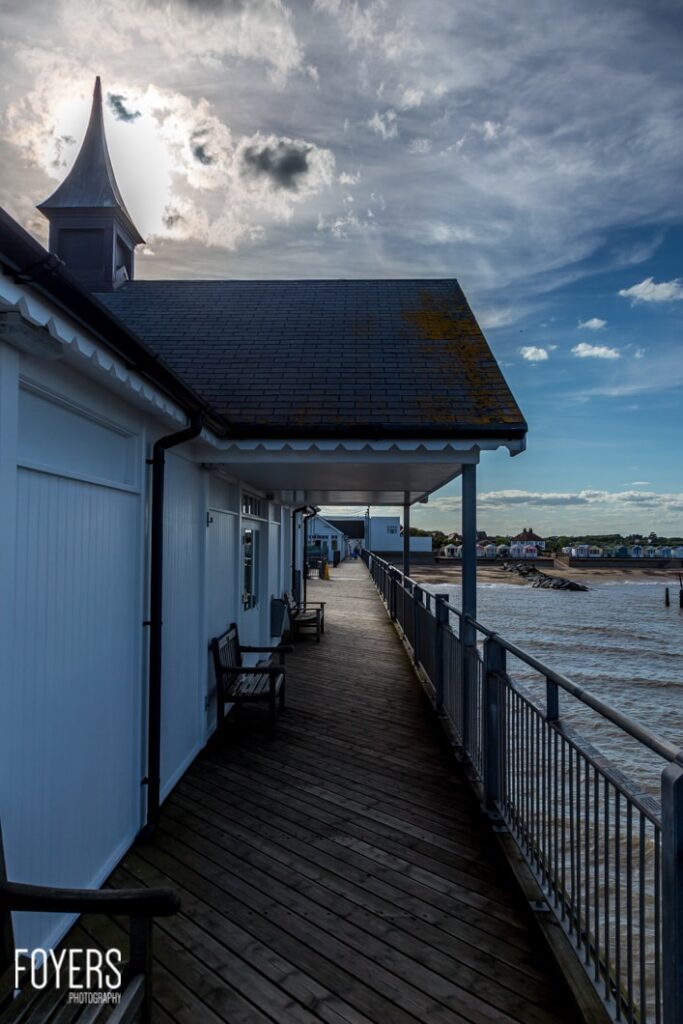Coastal boardwalk beside houses under cloudy sky