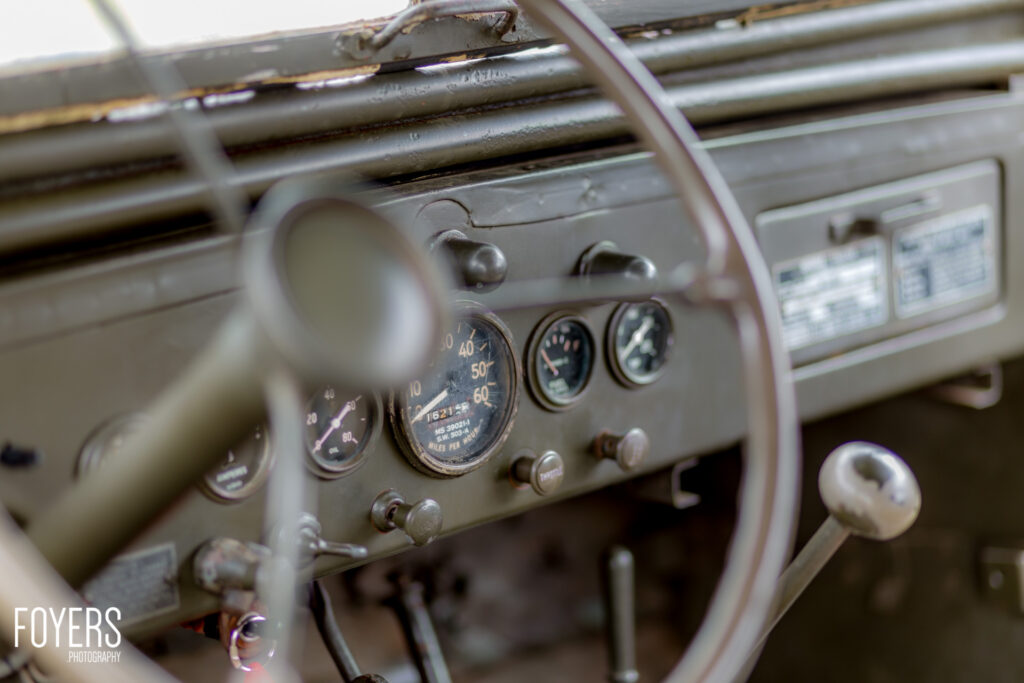Weathered dashboard and steering wheel of a vintage military vehicle showing aged gauges and controls