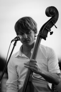 A musician performs with a cello and microphone in this black and white photograph.