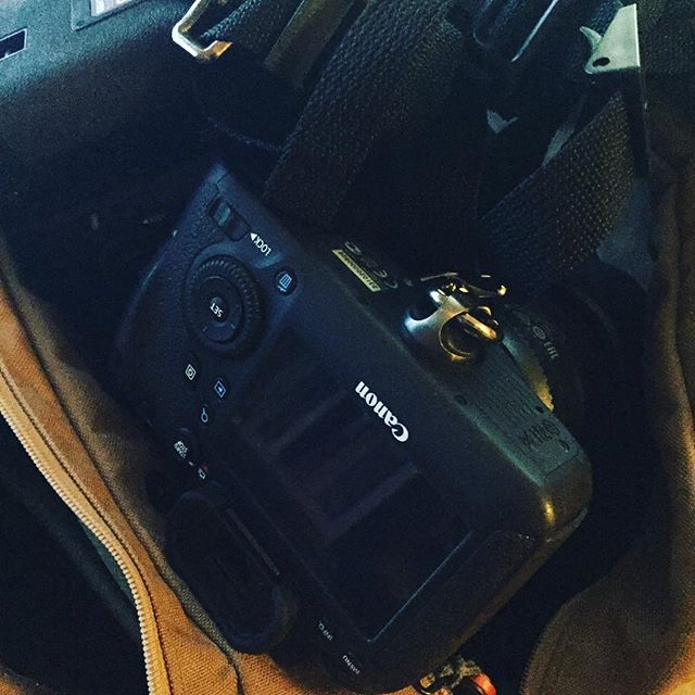 A Canon camera sits on a yellow and black fabric surface, photographed from above in dim lighting.