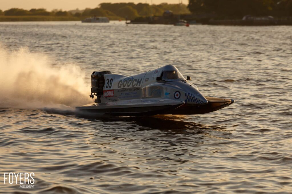 A speedboat numbered 39 named Gooch races across water, creating a spray of spray behind it.