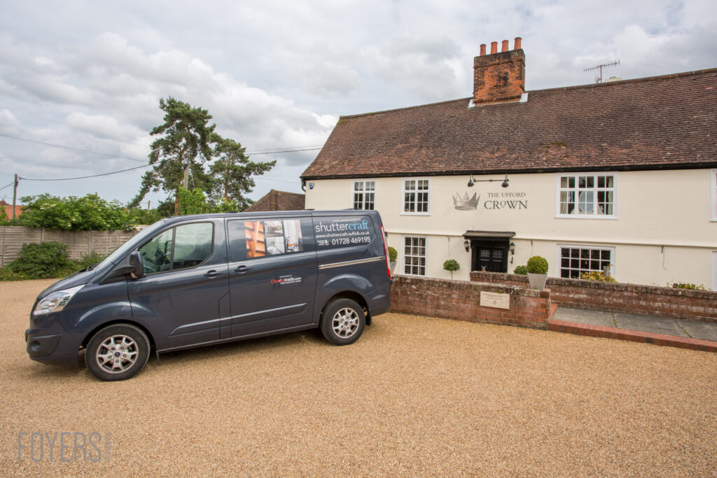 A dark blue van parked outside The Ufford Crown pub, a cream-coloured building with a brick chimney.
