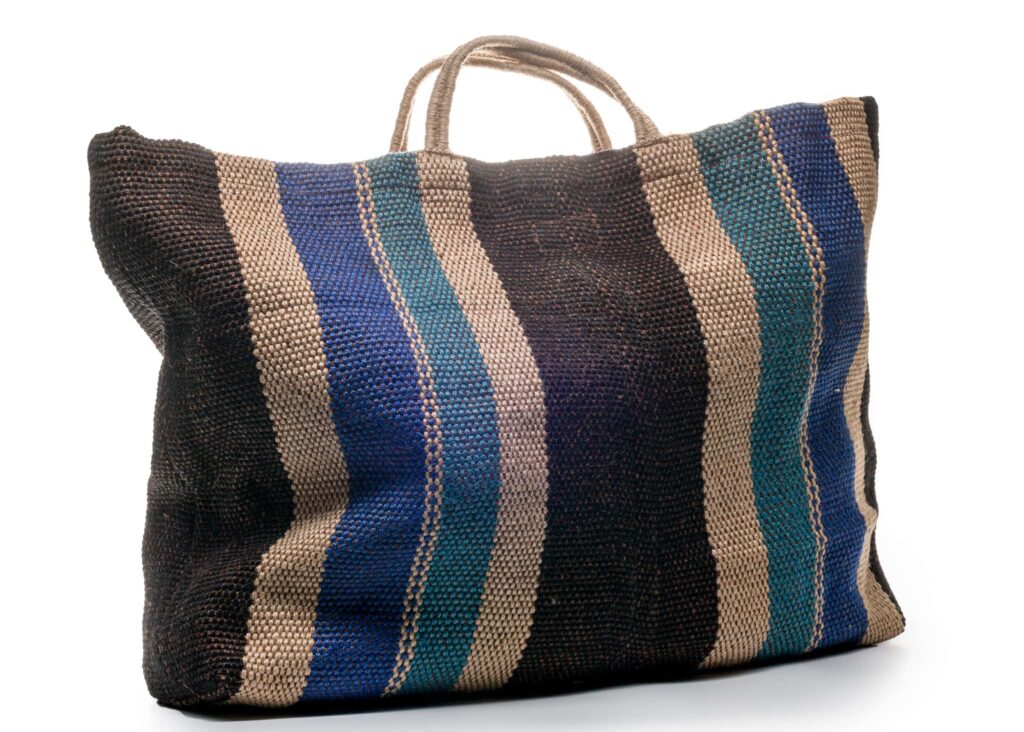 Striped woven tote bag with handles in charcoal, cream, blue and teal colours, displayed against a white background.