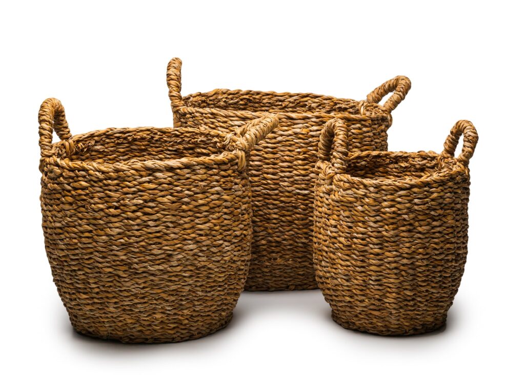 Three woven straw baskets with rope handles arranged against a white background.