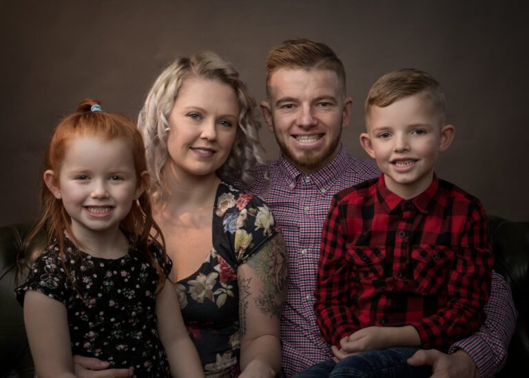 The George family of four photographed together against a warm brown studio backdrop