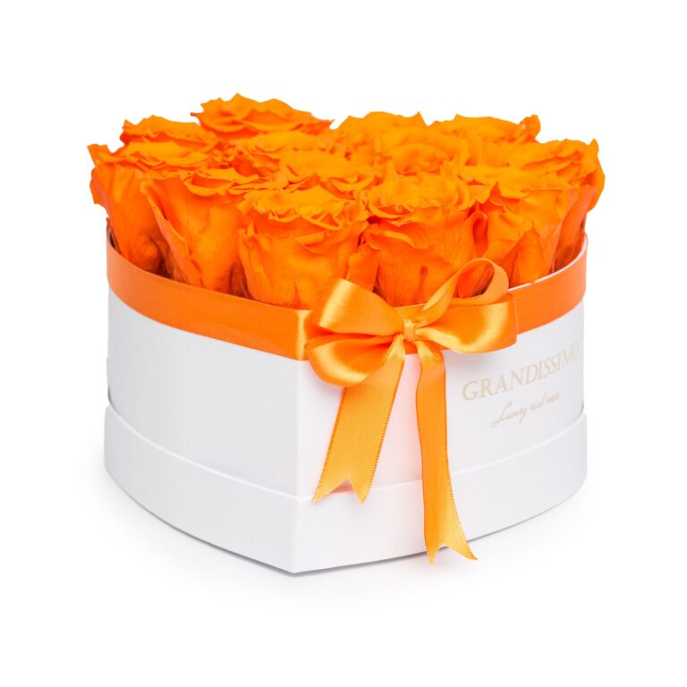 A heart-shaped white box filled with bright orange roses, tied with an orange satin ribbon bow.