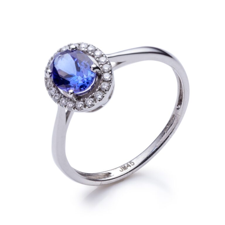 A white gold ring with a blue sapphire centre stone surrounded by small diamonds, displayed against a white background.