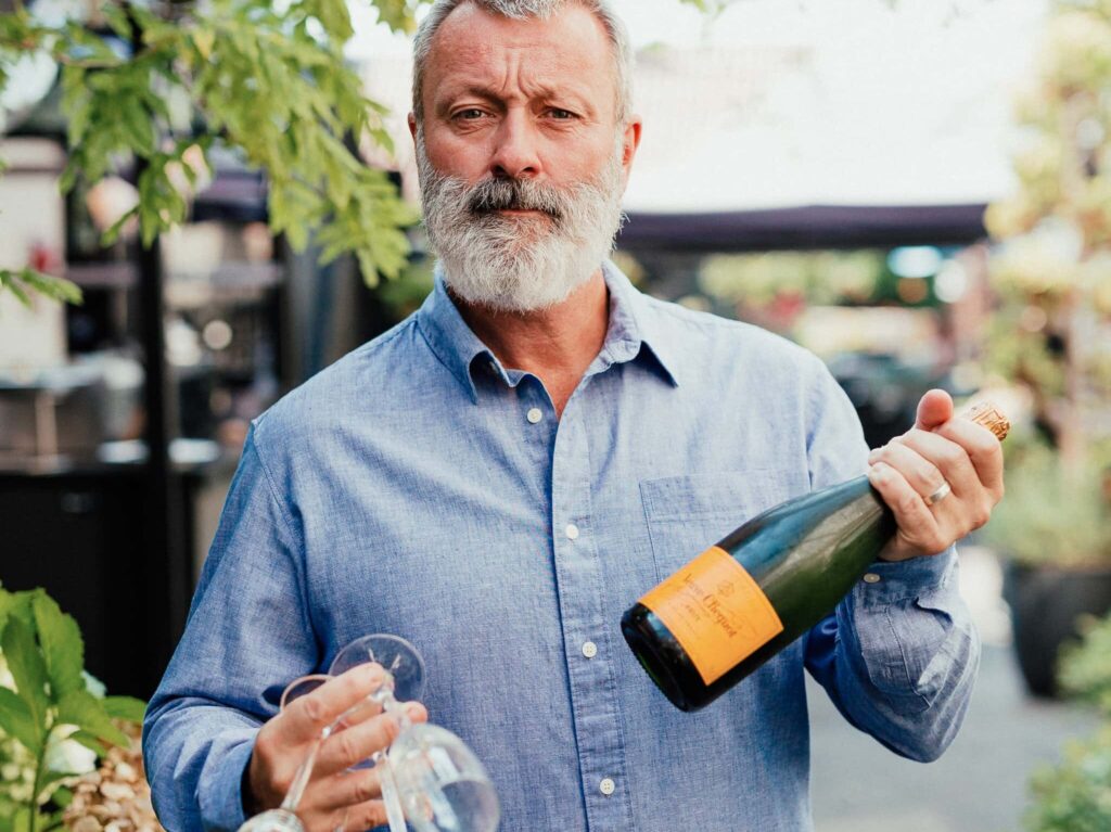Personal branding photograph of a man holding champagne and glasses at Graze at the White Horse
