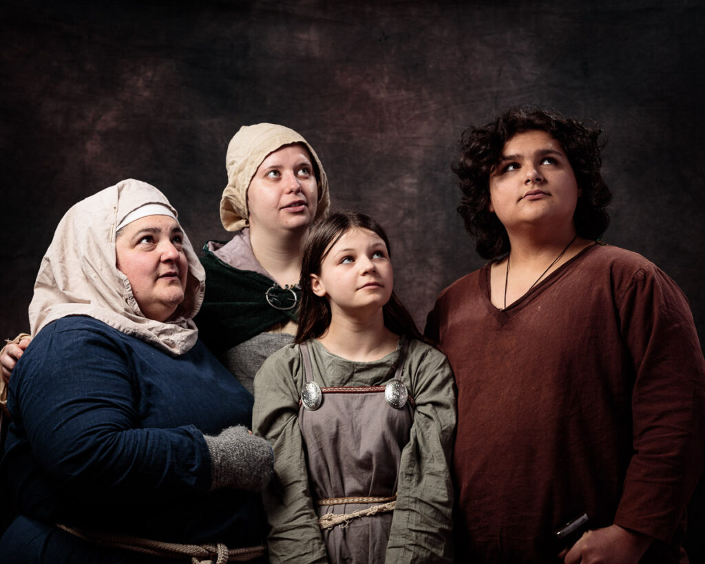 Four people in medieval costume looking upward against a dark textured background.