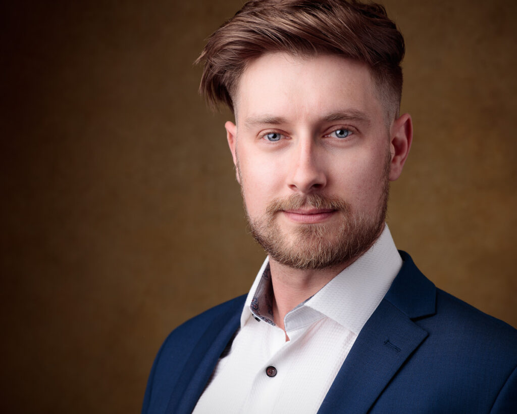 Man in blue suit with beard and short hair.