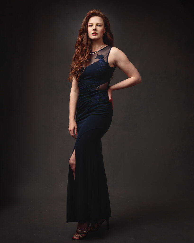 Full-length portrait of Isabelle in a navy lace-panel gown with a thigh split and strappy heels