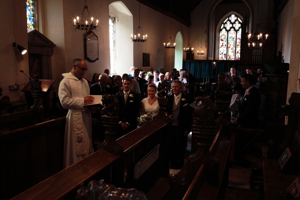 A wedding ceremony taking place in a church, with a priest conducting the service and the bride and groom at the altar.