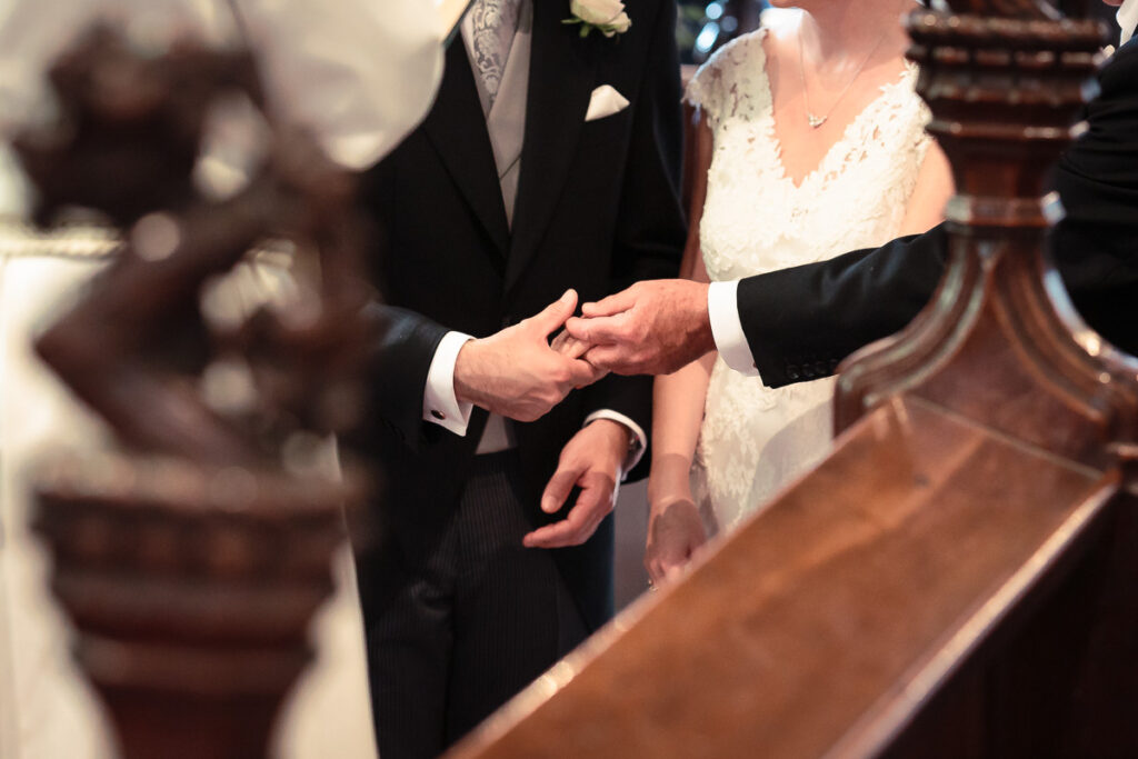 Bride and groom holding hands at altar during wedding ceremony in a church.