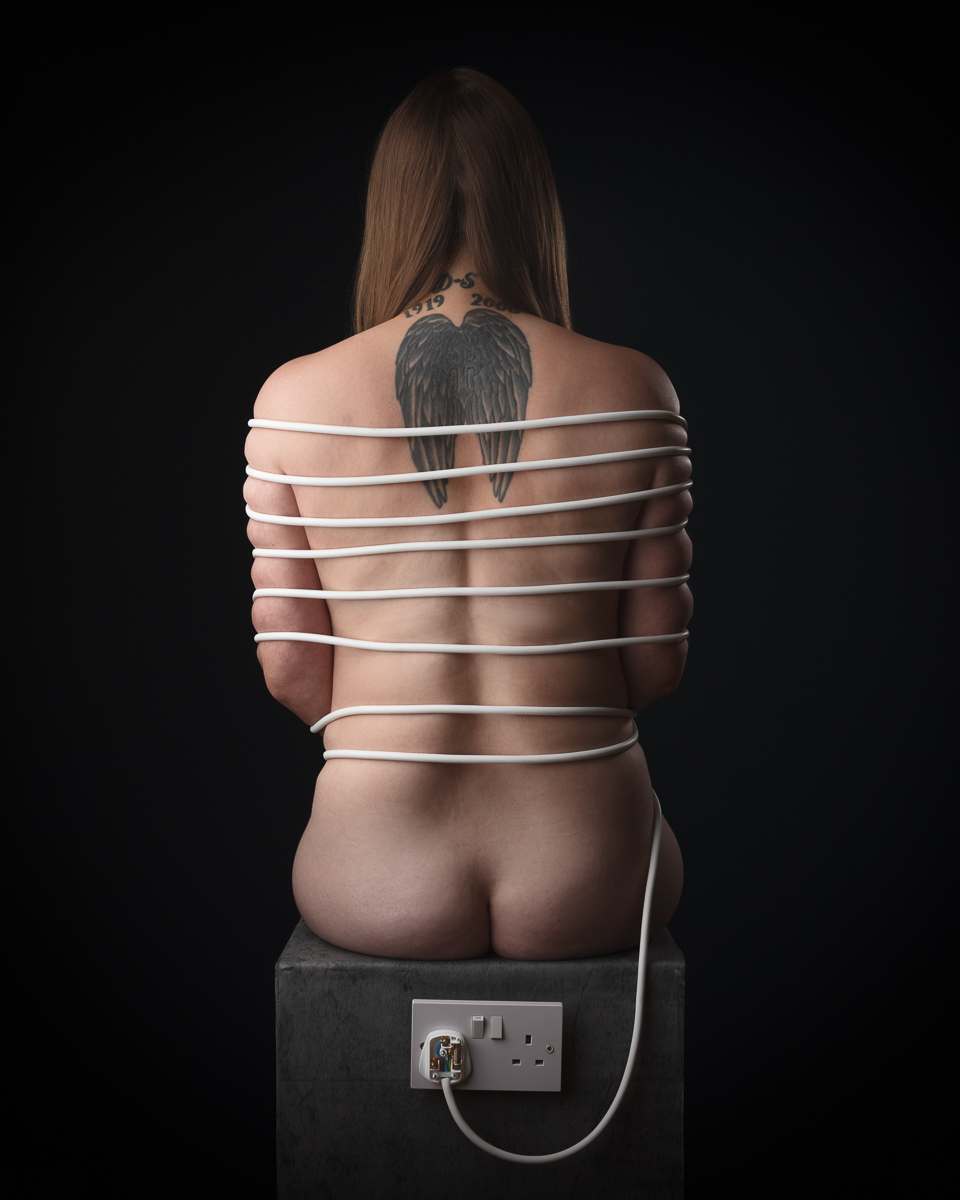 Person wrapped in cable with wing tattoo on back.