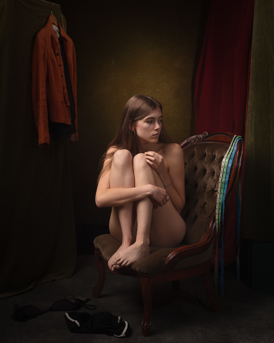 Woman sitting in chair surrounded by clothing.
