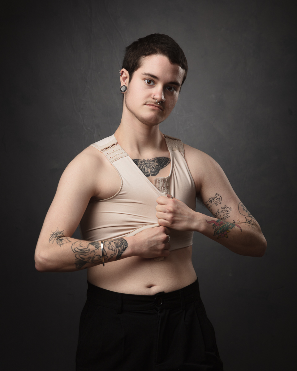 Person with tattoos adjusting beige top