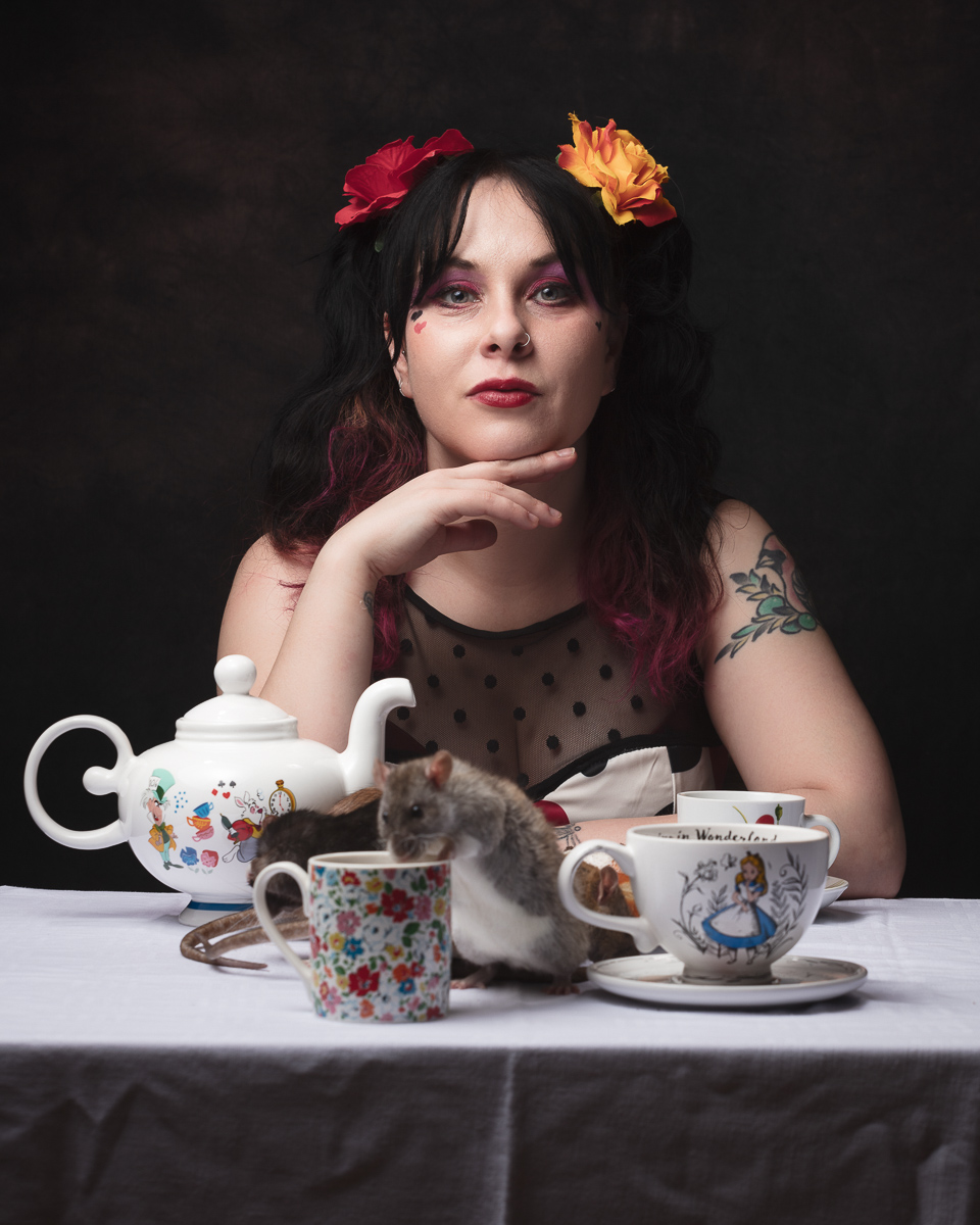 Person with flowers in hair, mouse on teacup.