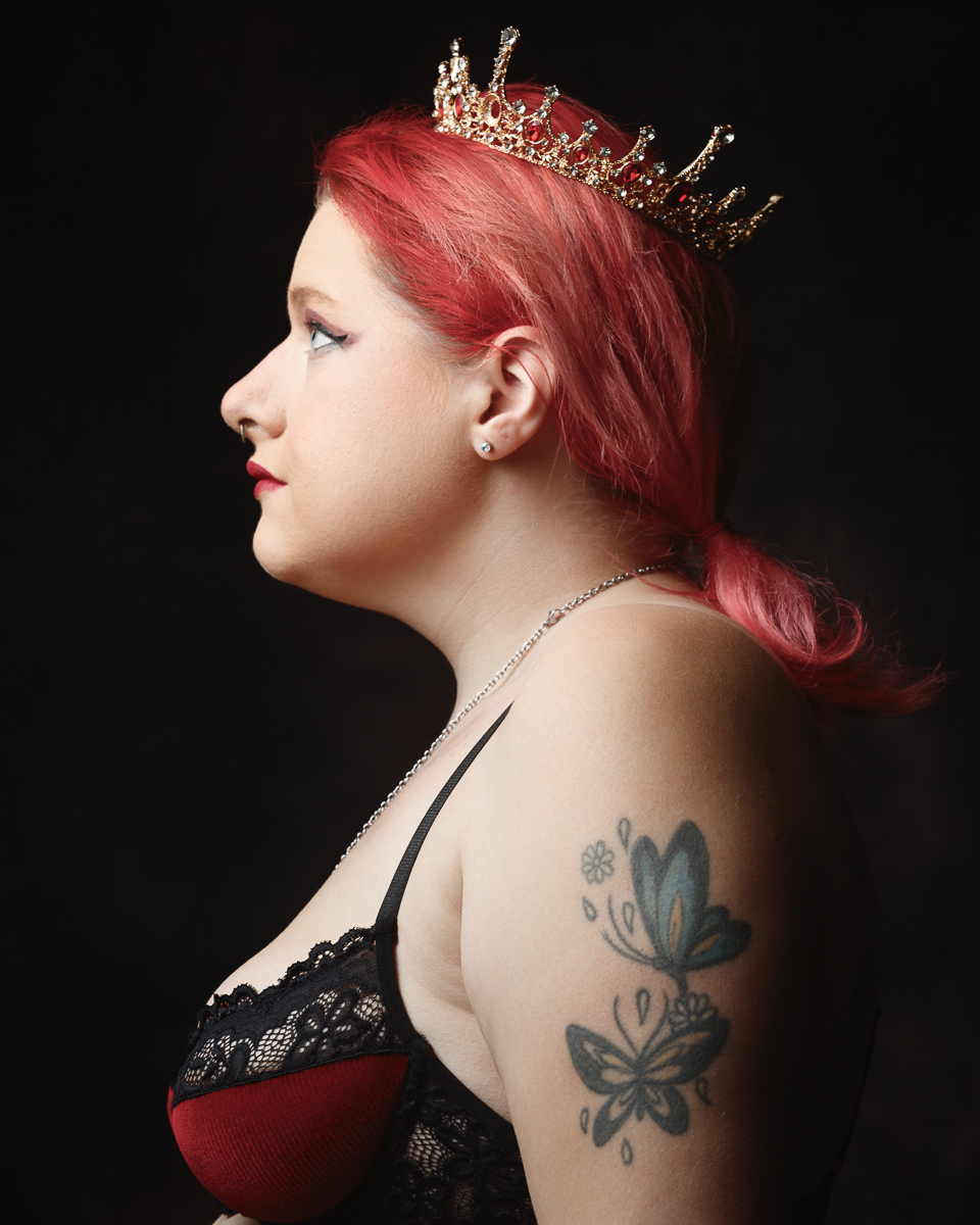 Person with crown, butterfly tattoo, side profile portrait.