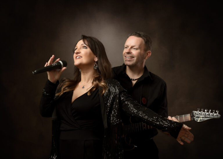 Female singer with microphone and male guitarist performing together