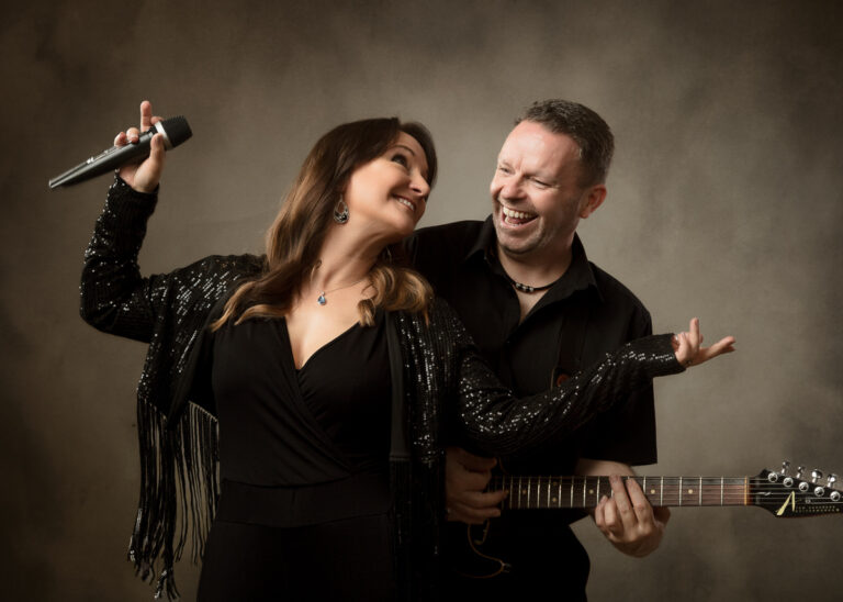 Female singer with microphone and male guitarist performing together