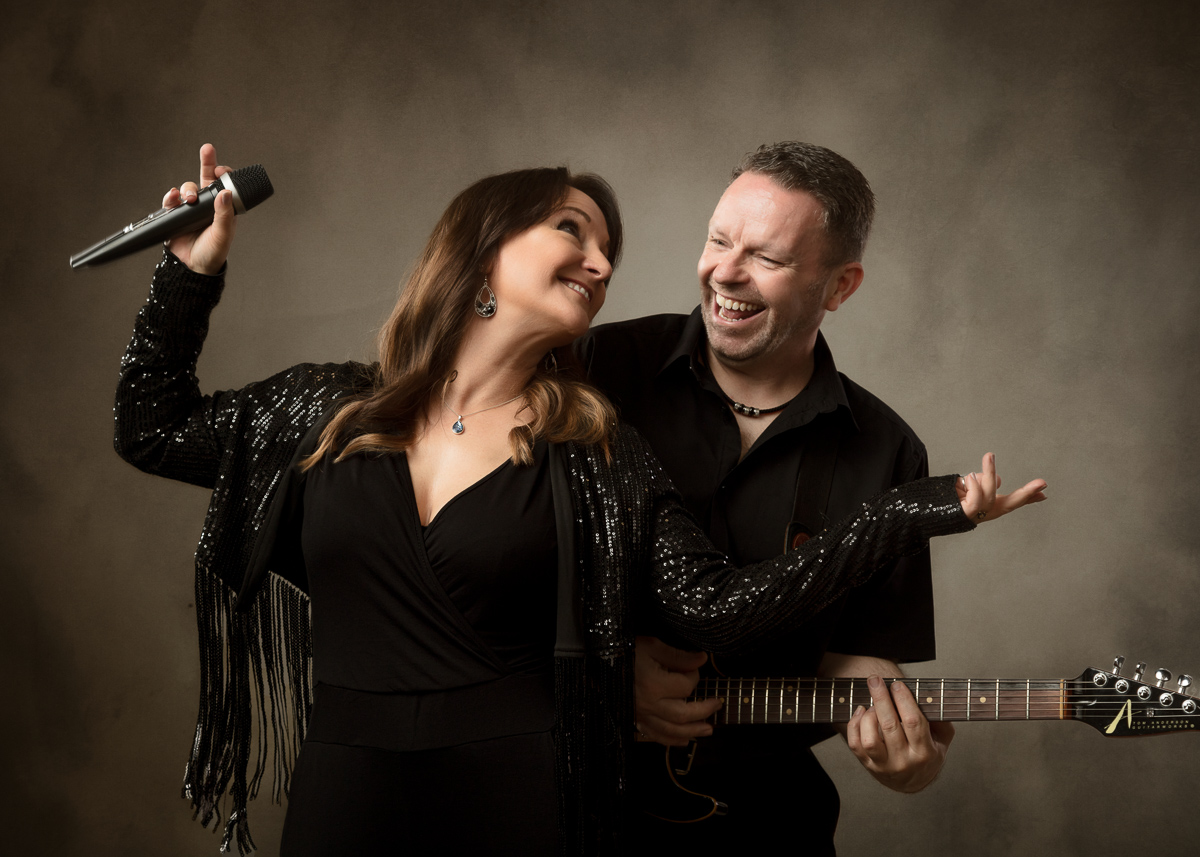 Female singer with microphone and male guitarist performing together