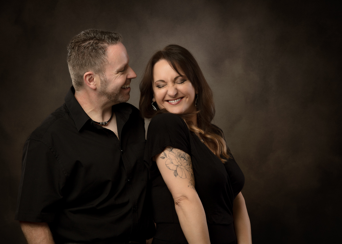 Couple posing together smiling against neutral brown background