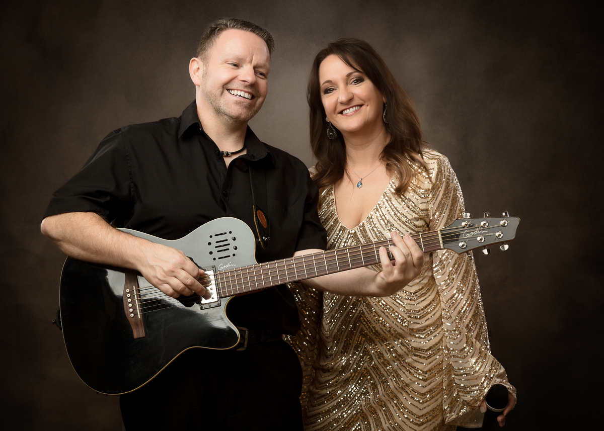 Man and woman smiling together holding acoustic guitar