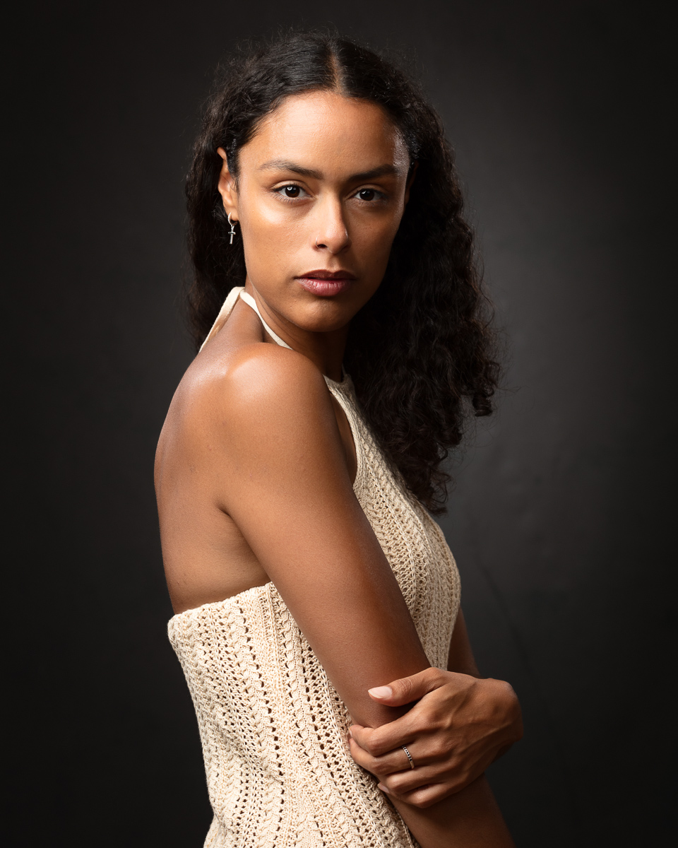 Professional portrait of woman with long dark hair wearing cream knit top