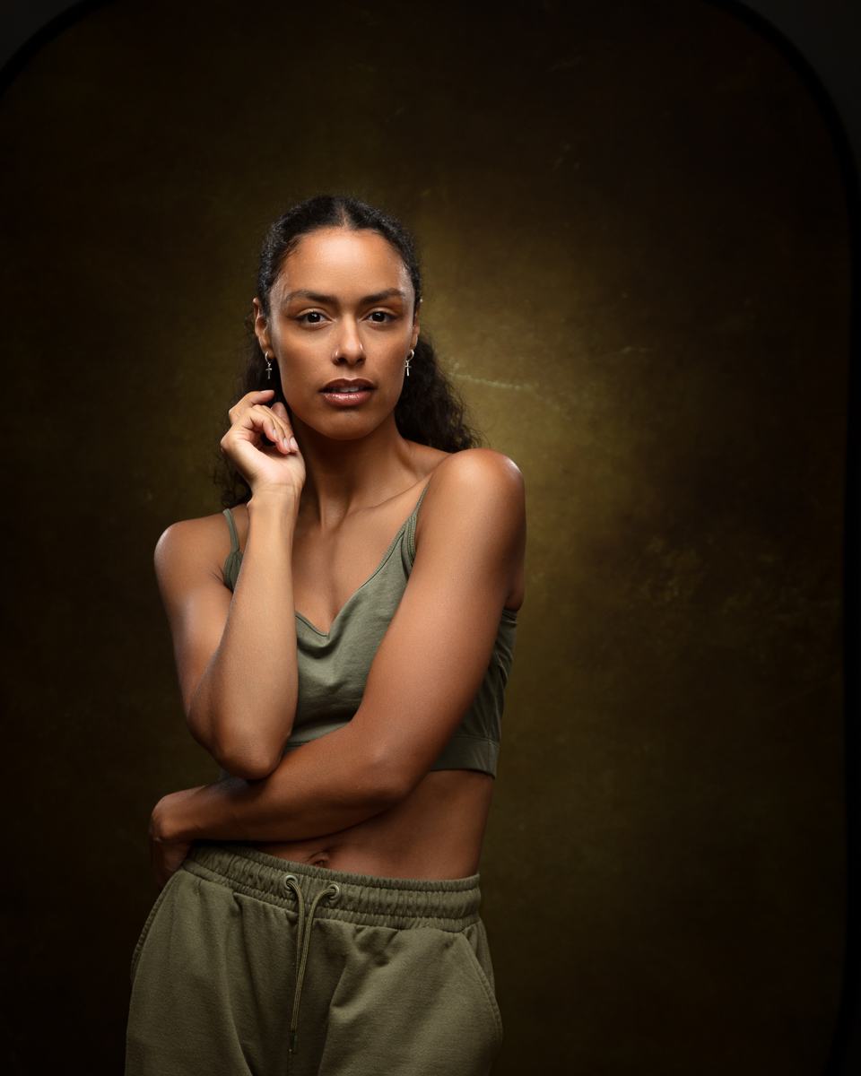 Woman in olive tank top posing against dark background