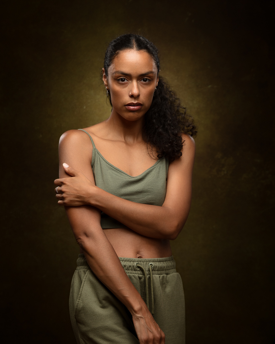 Woman in olive tank top and shorts against brown background