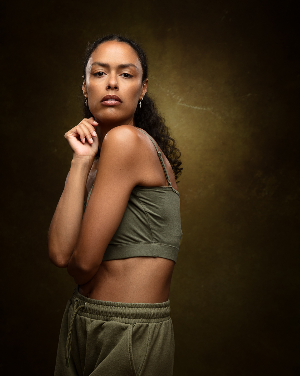 Woman in olive sports bra and shorts against golden background