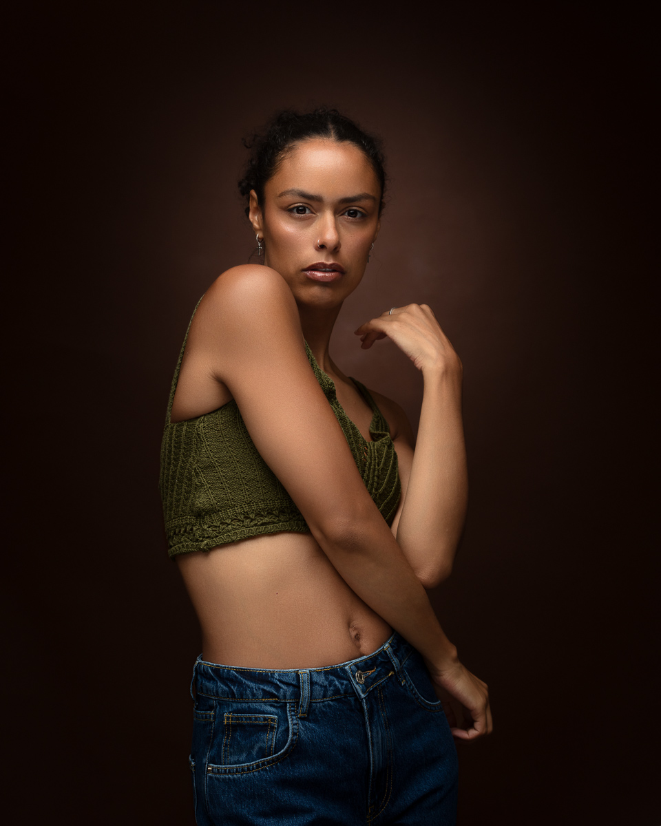 Woman in green halter top and jeans against brown background