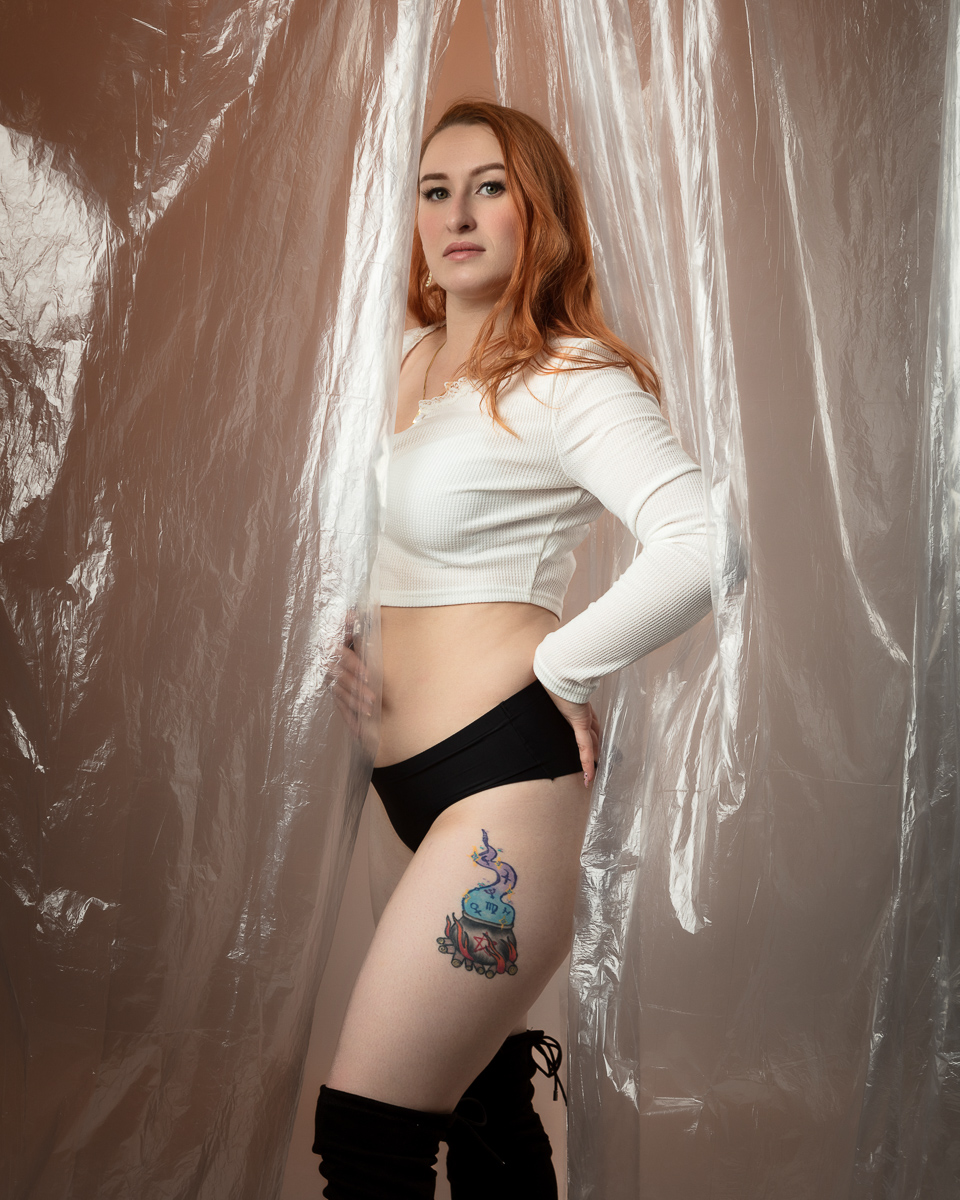 Woman with red hair and tattoo posing against textured background