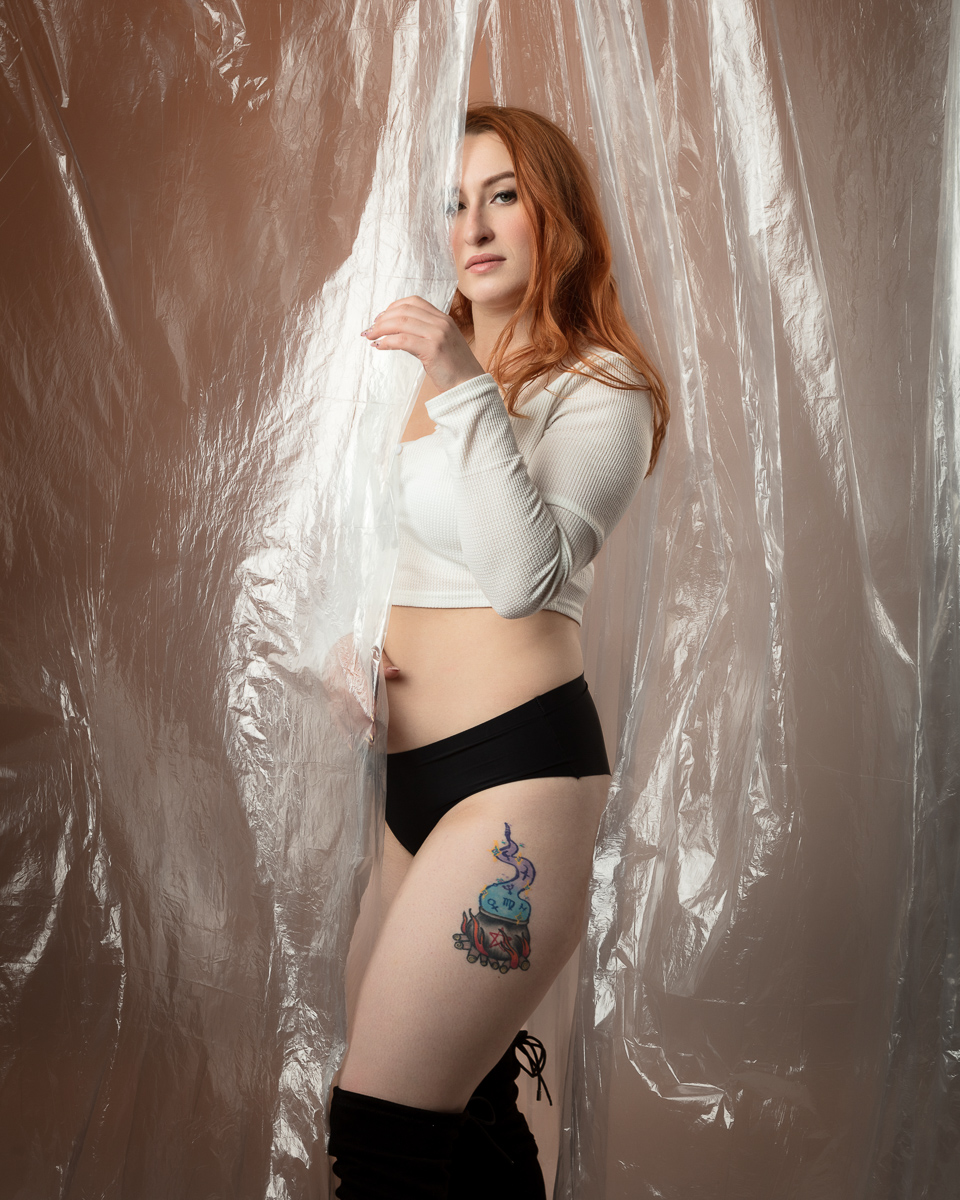 Woman with red hair and tattoos posing with plastic backdrop