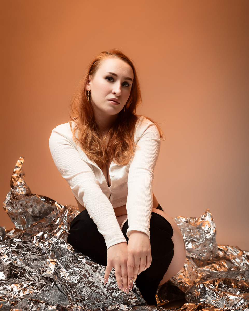 Woman with red hair crouching on metallic rocks
