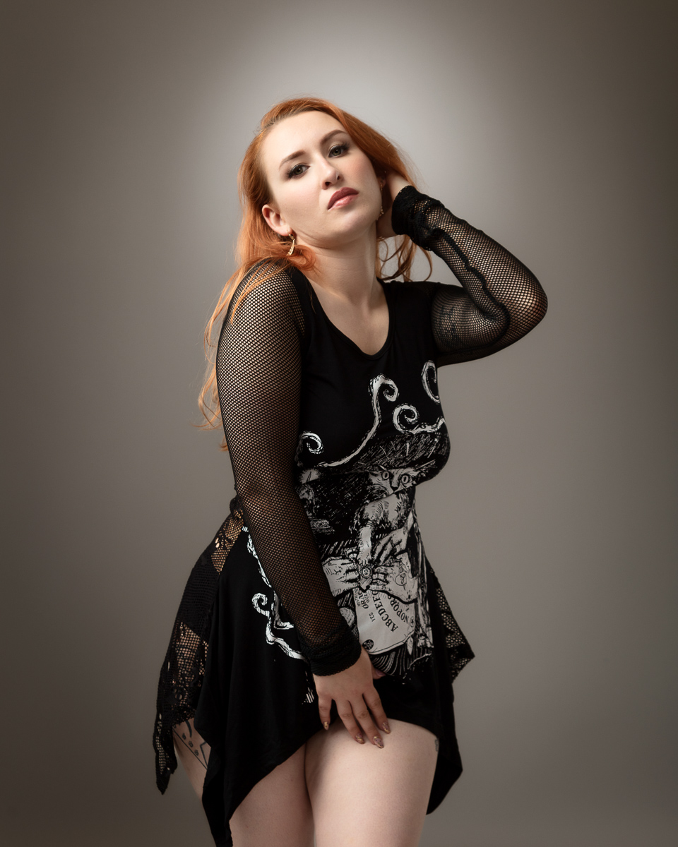 Woman with red hair wearing black graphic dress and mesh sleeves