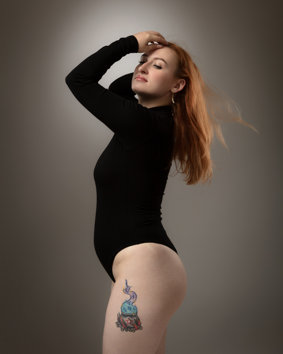 Woman with red hair and leg tattoo in black bodysuit