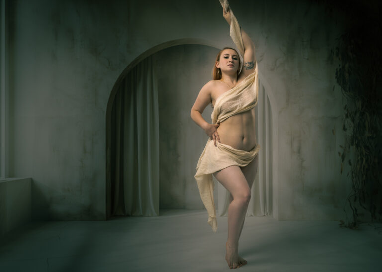 Woman in cream fabric posing in arched doorway studio