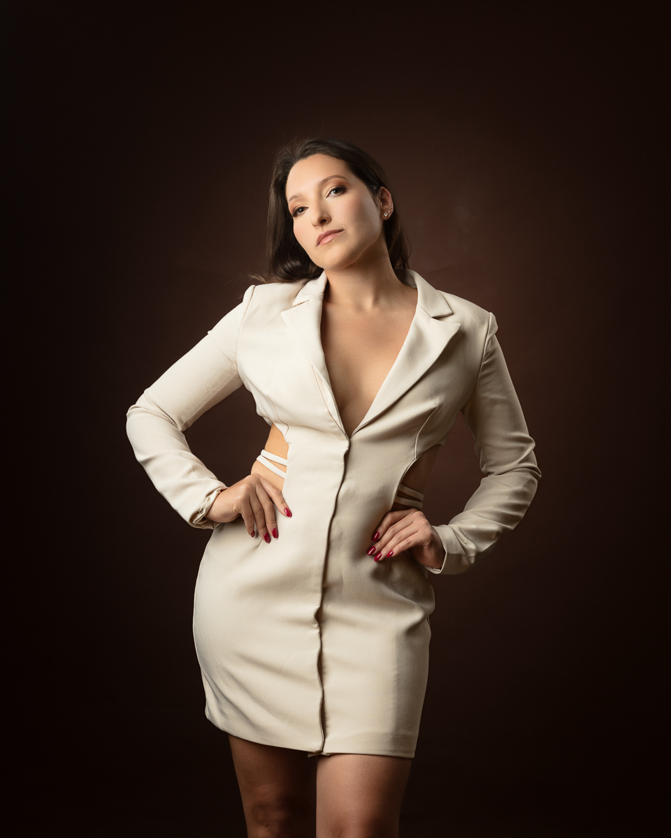 Woman in cream blazer dress against dark brown background