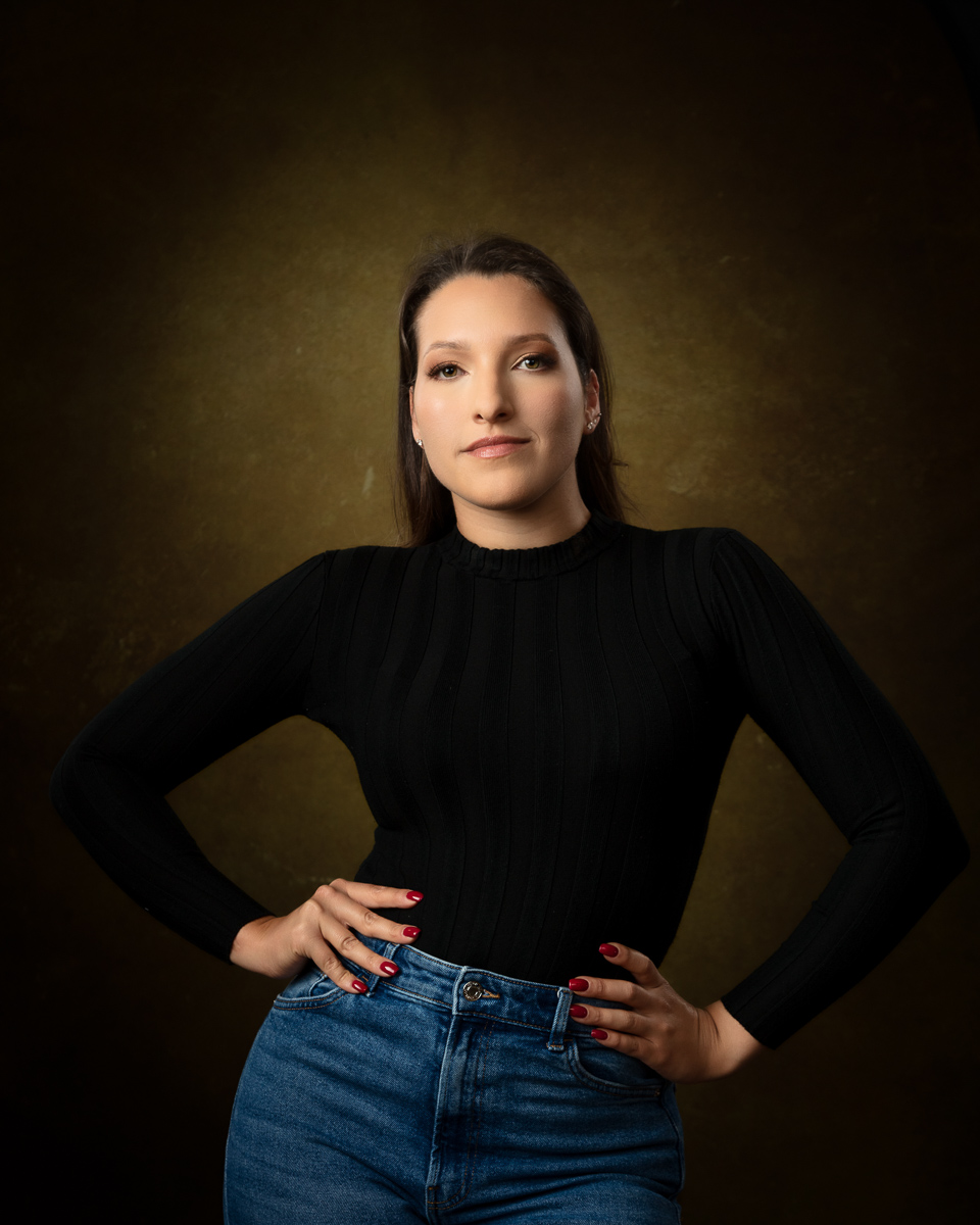 Woman in black top and jeans against golden background