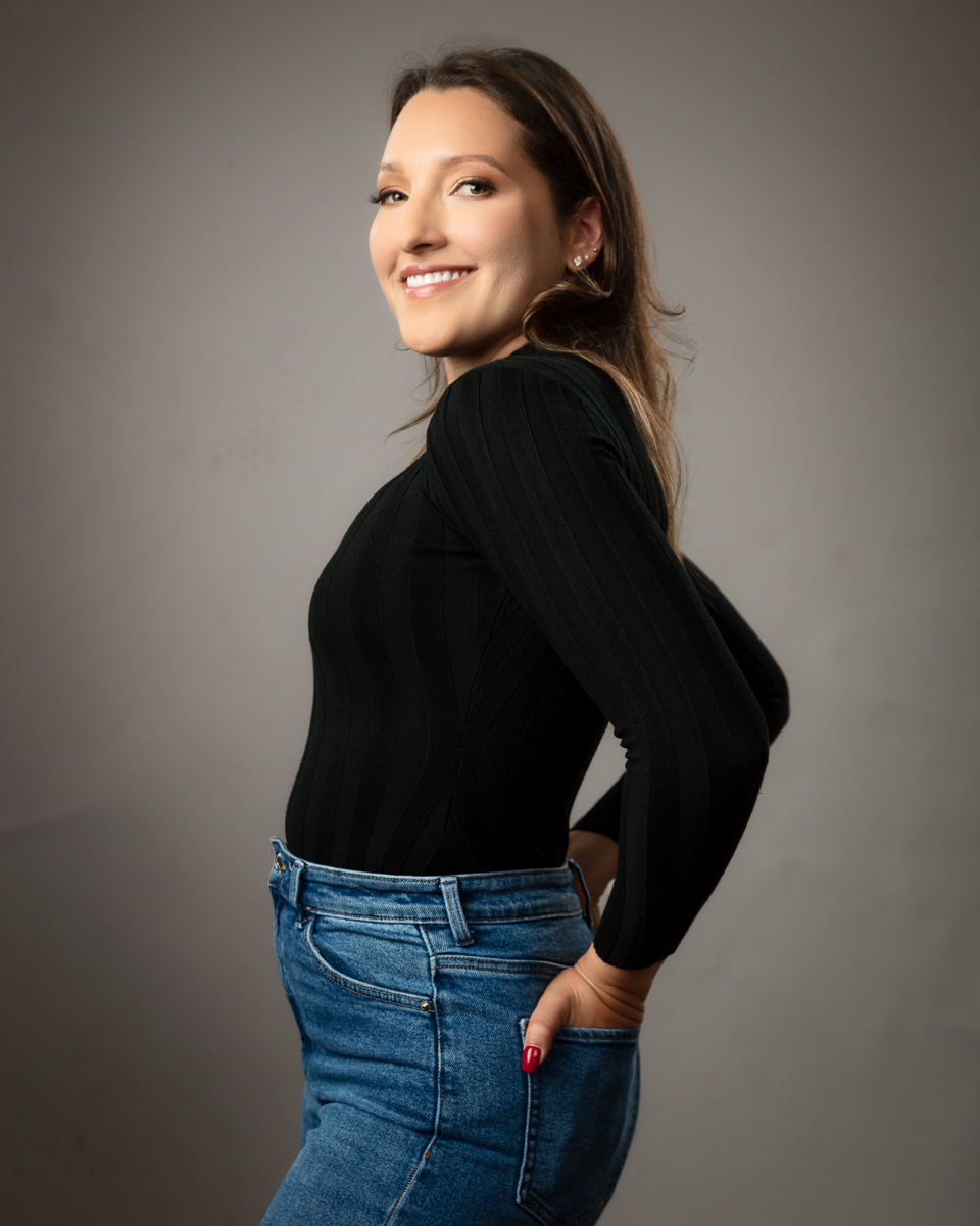 Woman smiling, wearing black top and blue jeans