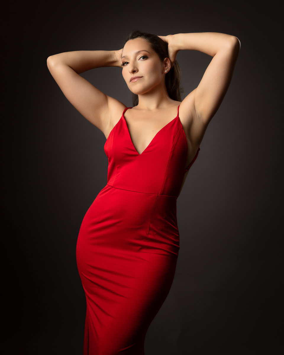 Woman in red dress posing with arms raised behind head